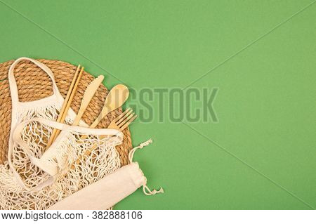 Reusable Wooden Cutlery And Grocery Bag. Eco Friendly Fork, Knife, Spoon And Stics On A Green Backgr