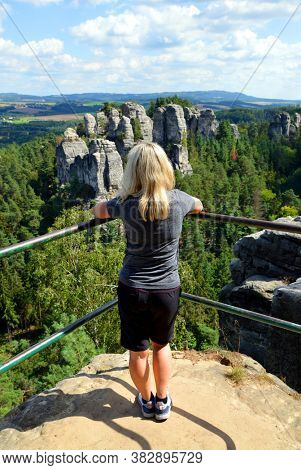 Woman looking at the view of rocky sandstone formations in Hruba Skala, Bohemian Paradise (Cesky Raj), Czechia.