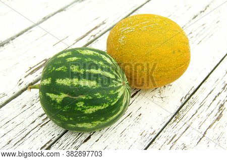 Assorted Homemade Melon And Watermelon On A Wooden White Background - A Table Grown In A Greenhouse.