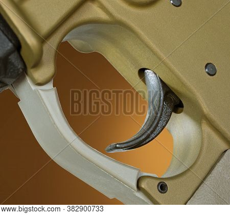 Copper Colored Ar-15 Trigger With A Brown Background