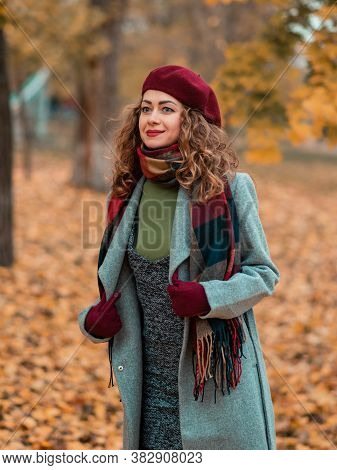 Girl In Gray Coat And Red Beter Or Hat. Lady Posing In Autumn Time Park