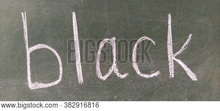 The Word Black Written By Hand On A Green School Board. Black Color. Printed Letters