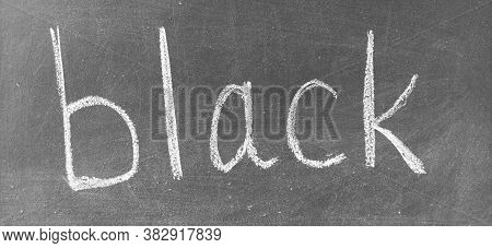 The Word Black Written By Hand On A Black School Board. Printed Letters. Monochrome Image