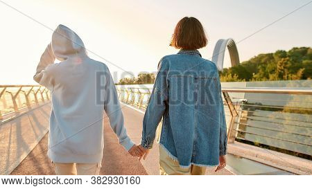 Lesbian Couple Hugging On The Bridge, Looking At Each Other Before Kiss While Admiring The Sunrise T