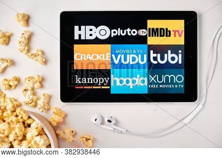 Movies Application Logo On The Screen Of The Tablet Laying On The White Table And Sprinkled Popcorn 