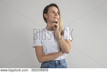 Woman With Blonde Hair Looking Aside Up Holding Hand Under Chin Indenting To Realize Tricky Plan. At