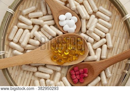 Vitamins, Minerals And Nutritional Supplements In Wooden Spoons Inside A Braided Bamboo Plate. Top V