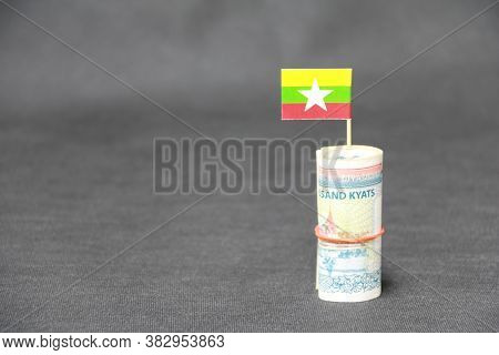 Rolled Banknote Money Ten Thousand Myanmar Kyats And Stick With Mini Myanmar Flag On Dark Grey Floor
