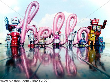 robots holding up the word hello on a old wooden floor with reflection