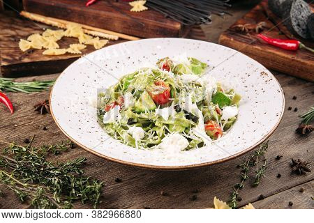 Italian Green Fettuccine Pasta With Tomatoes And Cheese On The Decorated Wooden Table