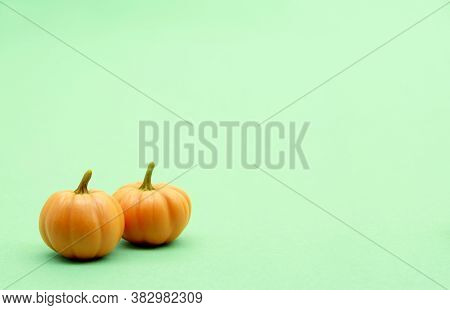 Two Small Pumpkins On A Pastel, Green, Delicate Background.the Concept Of The Fall Decor. Side View.