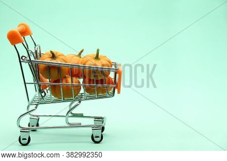 A Composition Of Tiny Pumpkins In A Supermarket Cart On A Soft Green Background. The Concept Of Sell