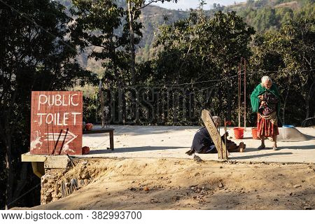 Two Elderly, Charismatic Nepalese Ladies, Smoking  Near The Sign 