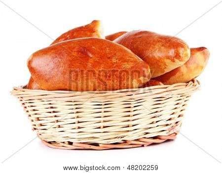 Empanadillas al horno frescos en cesta de mimbre, aislados en blanco