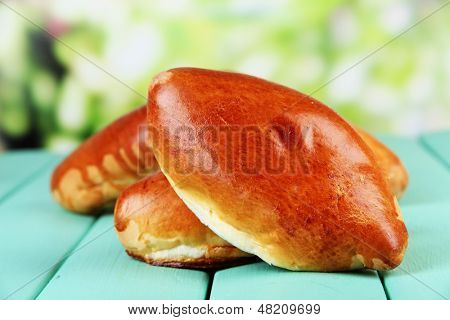 Empanadillas al horno frescos, en mesa de madera, sobre fondo brillante