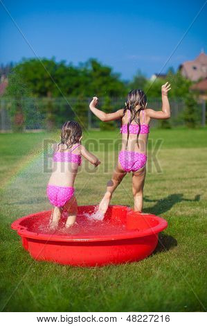 To små søstre Frolicing og sprøjt i deres gård i lille Pool