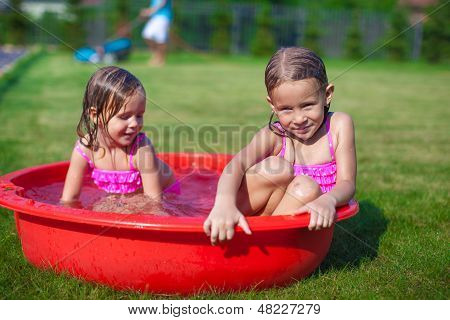 To Cute Little Sisters Frolicing og sprøjt i deres gård i lille Pool
