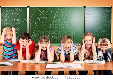 Grupo de crianças de escola cansadas em um grabing de sala de aula suas cabeças. Educação.