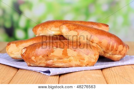 Empanadillas al horno frescos, en mesa de madera, sobre fondo brillante