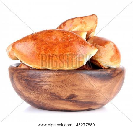 Empanadillas al horno frescas en un recipiente de madera, aislados en blanco