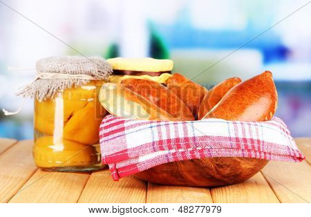 Empanadillas al horno frescos con mermelada de frutas, en la mesa de madera, sobre fondo brillante