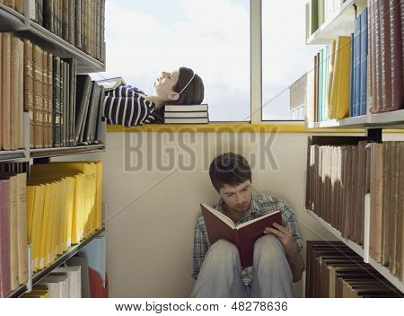 Masculinos e femininos os alunos a ler livros na biblioteca 