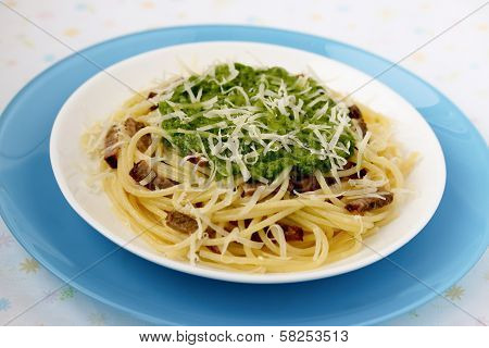 Italian pasta with pesto sauce on a blue plate.