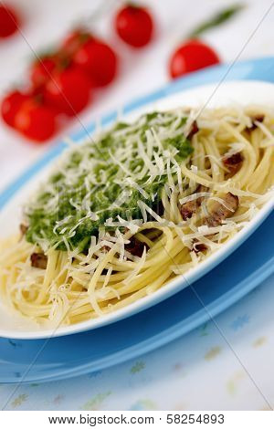 Italian pasta with pesto sauce on a blue plate.