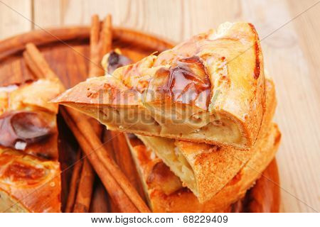 sweet food : cuts of apple pie on wooden plate over table with cinnamon sticks