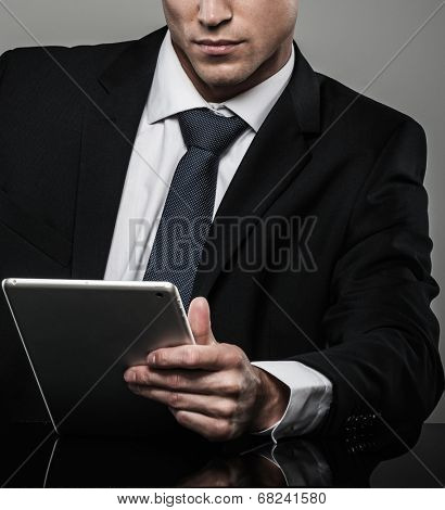 Well-dressed man in black suit with tablet pc