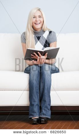 Felice donna seduta sul divano con il libro