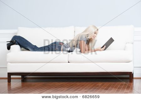 Donna sdraiata sul divano con il libro