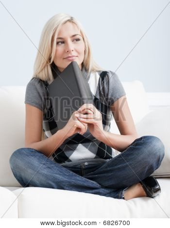 Donna contemplativa seduto sul divano e tiene un libro