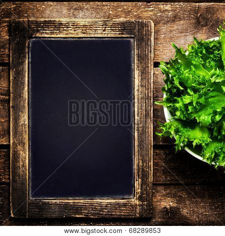 Black Chalkboard For Menu And Fresh Salad Over Wooden Background. Diet Food Restaurant And Healthy L