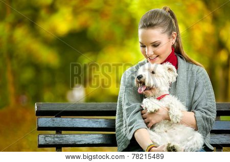 Young woman holding cute maltese dog,  outdoor in park 