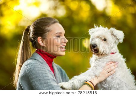 Cheerful girl with her cute puppy maltese in autumn park