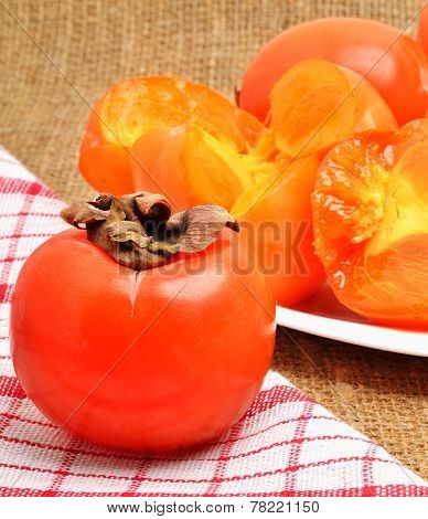 Ripe Persimmon Fruits On White Plate And Napking,  Sacking Background