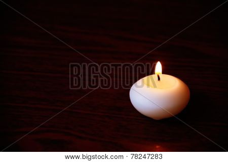 Single Candle On A Dark Wooden Table. Close Up Shot With Selective Focus.