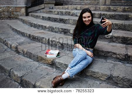 Young charming girl smiling while taking a self-ie outdoors