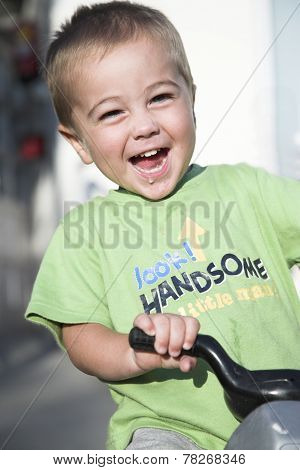 Handsome little boy rides toy motorbike, outdoor