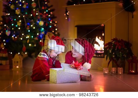Kids Opening Christmas Presents At Fireplace