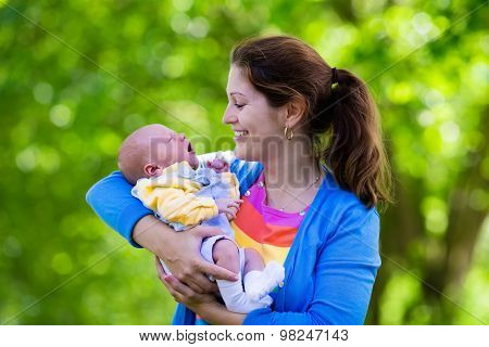 Mother Holding Newborn Baby In A Park