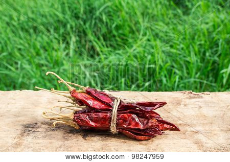 Dried Chili Peppers On Wooden With Green Grass Background