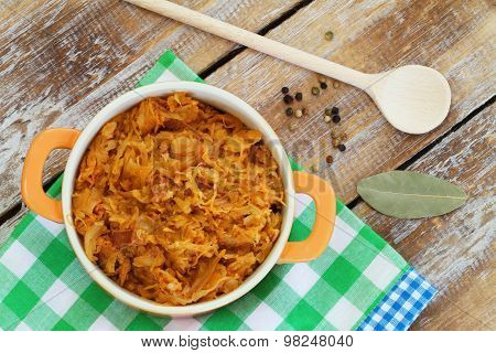 Polish bigos in saucepan on rustic wooden surface