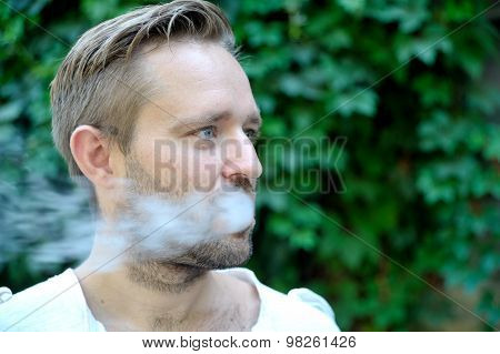 Side View Of Young Bearded Man Is Smoking