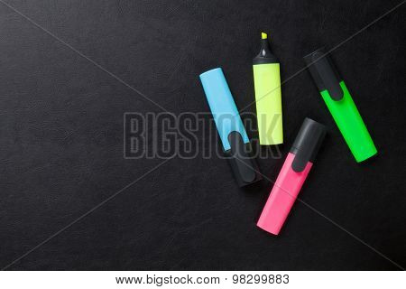 Colorful highlighters on leather desk table. Top view with copy space