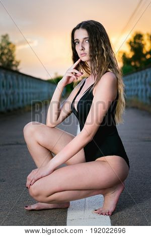 portrait of young woman in swimsuit posing in the middle of an empty road