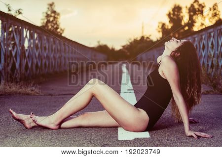 portrait of young woman in swimsuit posing in the middle of an empty road