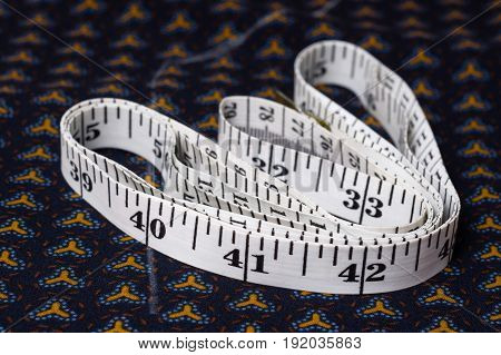 Inch, Centimeter Tape On A Background Of Blue Fabric With A Pattern