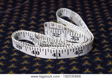 Inch, Centimeter Tape On A Background Of Blue Fabric With A Pattern